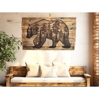 This is a large wood wall hanging featuring a bear and a forest scene. The rustic wall decor is hanging in an entryway over a bench. 